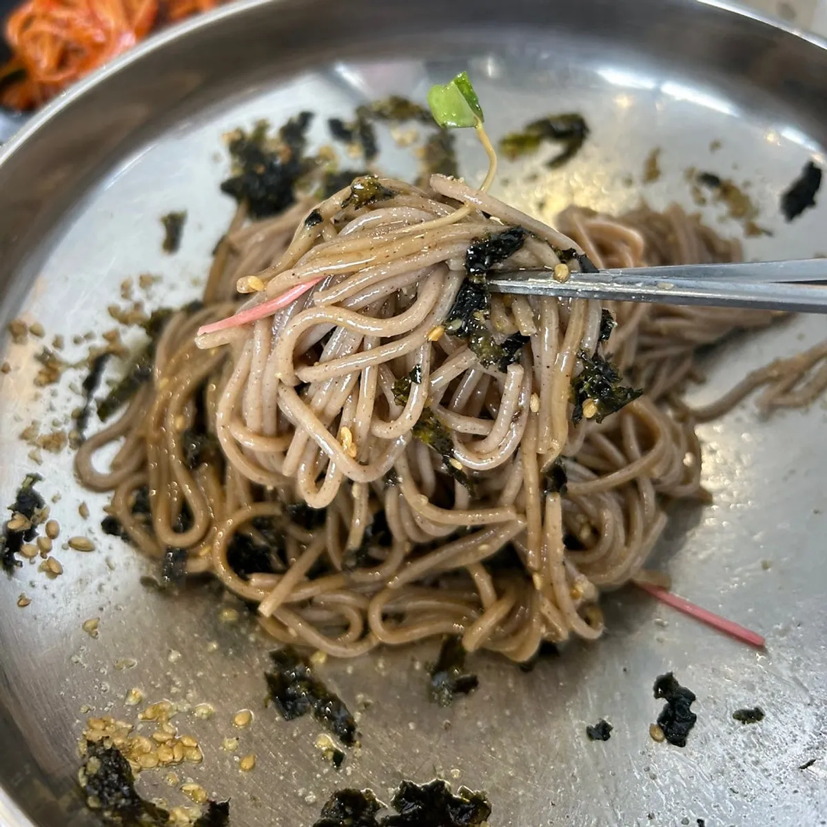 Close-up of perilla oil makguksu topped with seaweed flakes