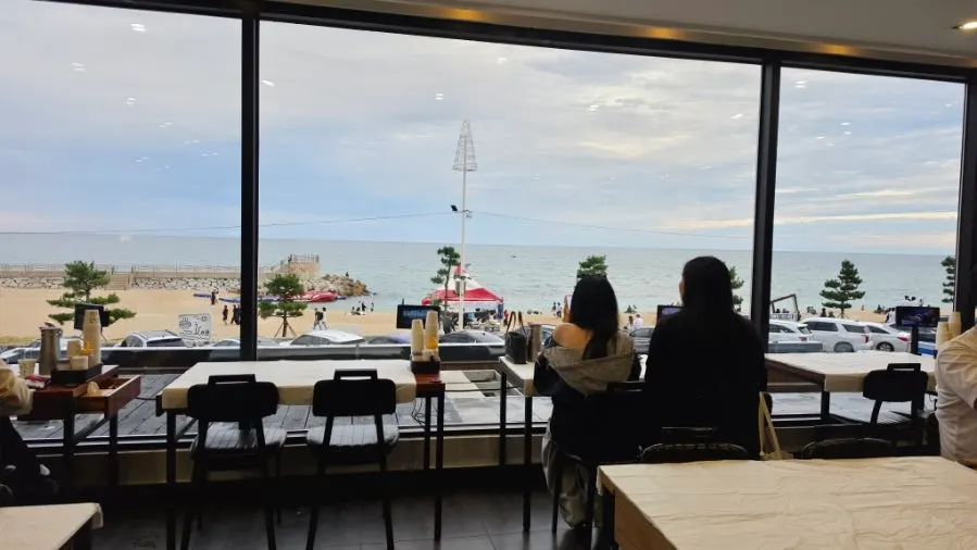 4-person table by the second-floor window with Gangmun Beach outside