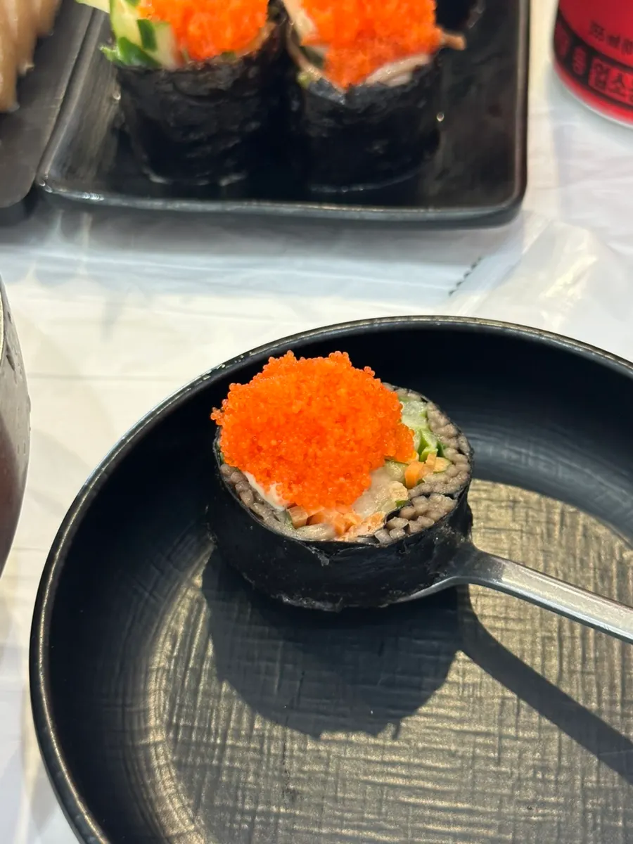 A bite-sized piece of flying fish roe buckwheat gimbap being picked up