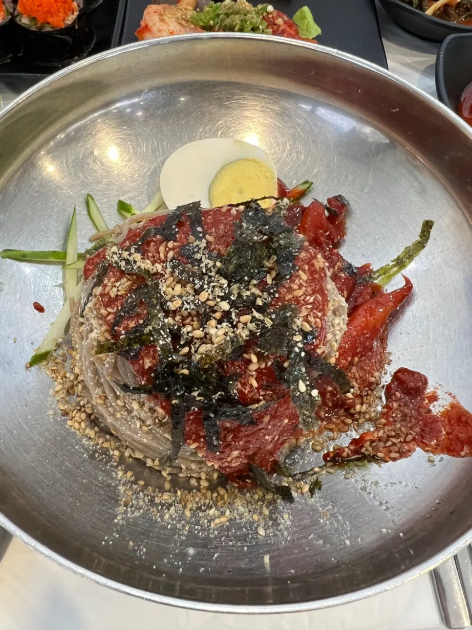 A bowl of spicy makguksu topped with seasoning
