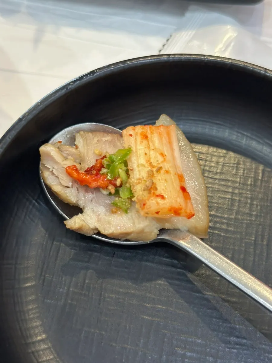 A piece of boiled pork ready to be wrapped with scallion salad