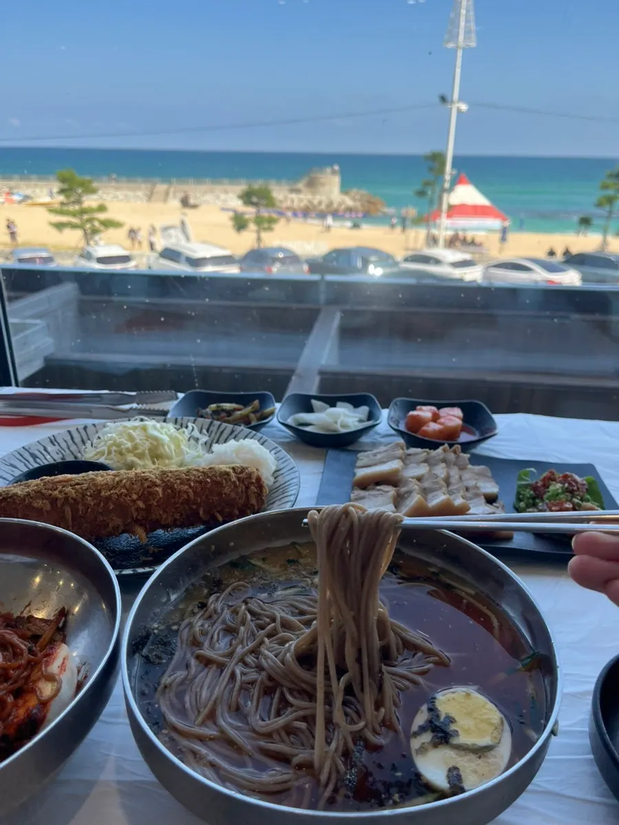 Food laid out on the window-side table with the sea in view