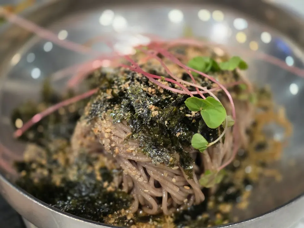 Perilla oil makguksu topped with roasted seaweed flakes and sesame seeds