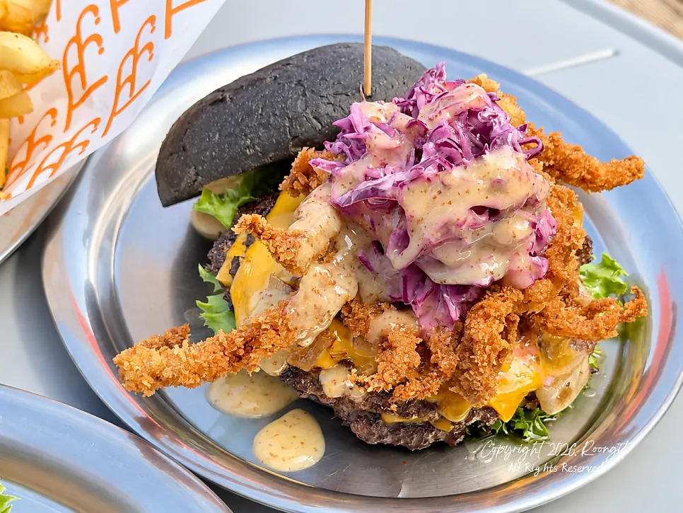 Cross-section of the squid burger with vegetables and coleslaw in a squid-ink bun