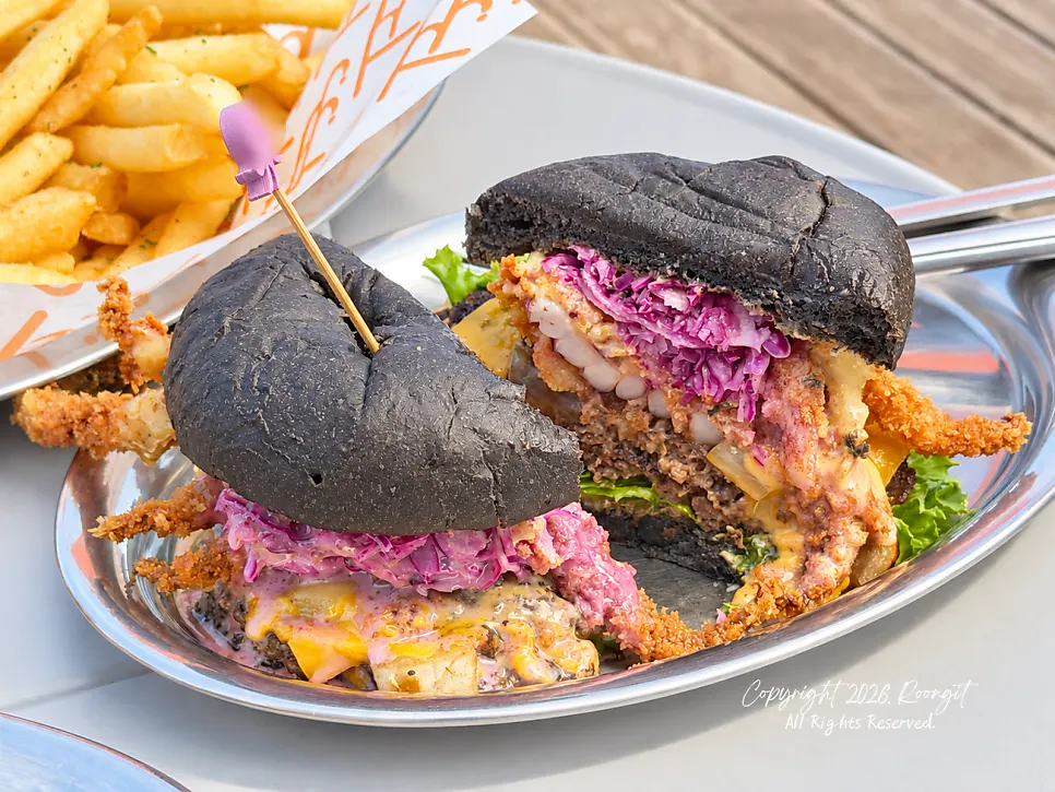 Close-up of the fried squid leg between the black squid-ink buns