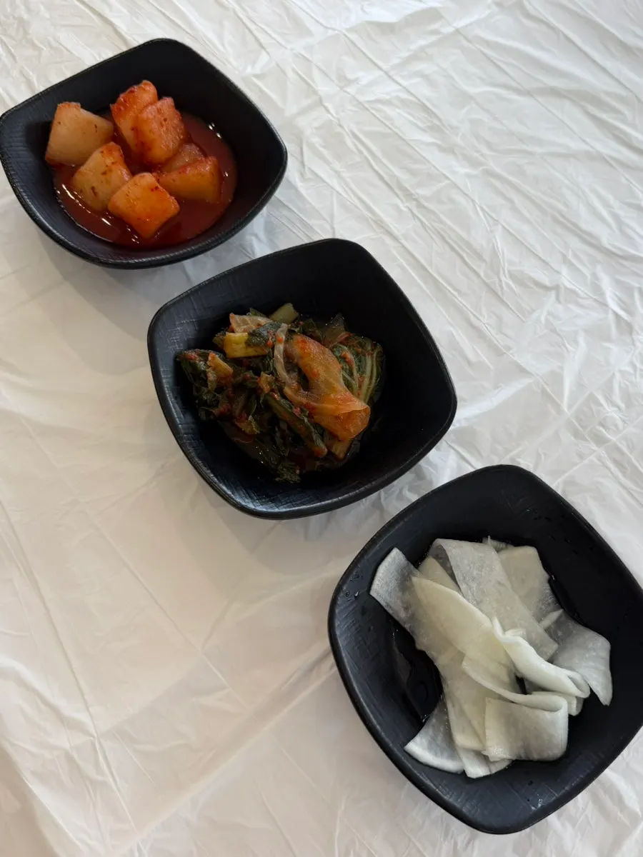 A full spread of basic side dishes served with makguksu