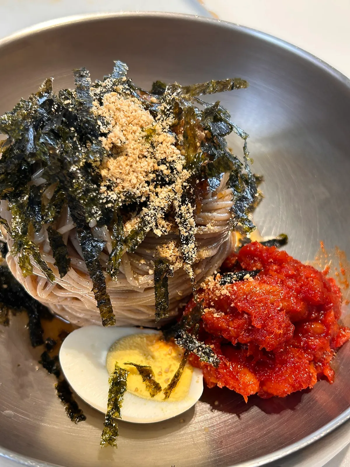 A spread of makguksu and hoe-makguksu topped with seasoned pollack