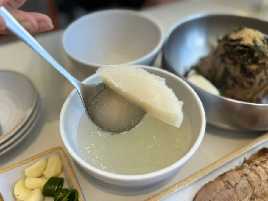 동치미 육수를 국자로 막국수에 붓는 모습