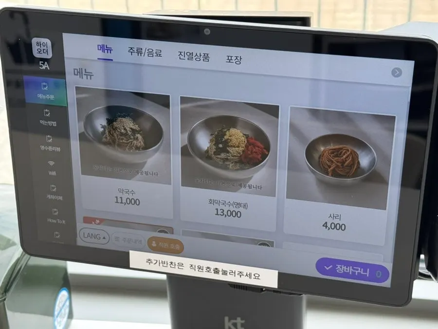Menu board listing dongchimi makguksu, pollack sashimi makguksu, and boiled pork