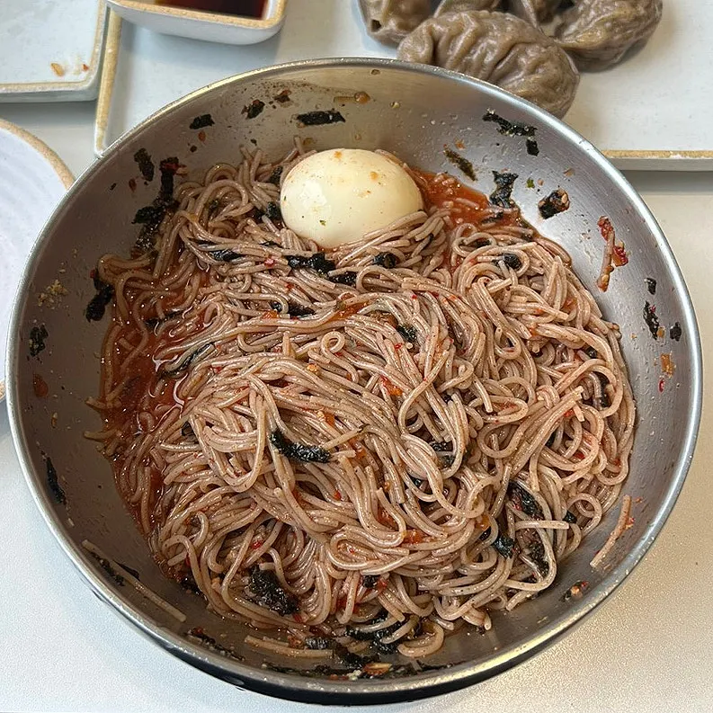 Chopsticks lifting a bite of makguksu noodles