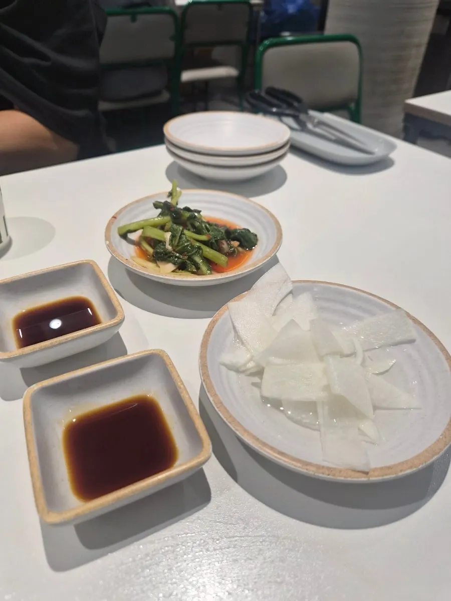Side dishes and dongchimi broth with a light layer of ice served at the table