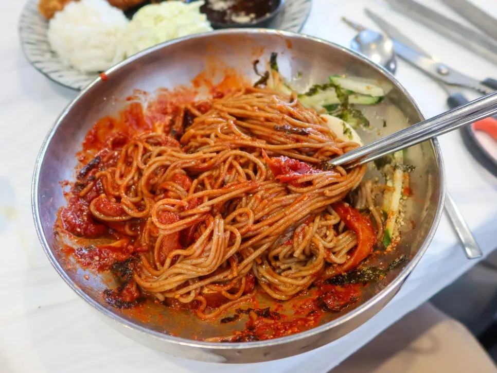 Spicy mixed makguksu topped with seasoned fermented pollock