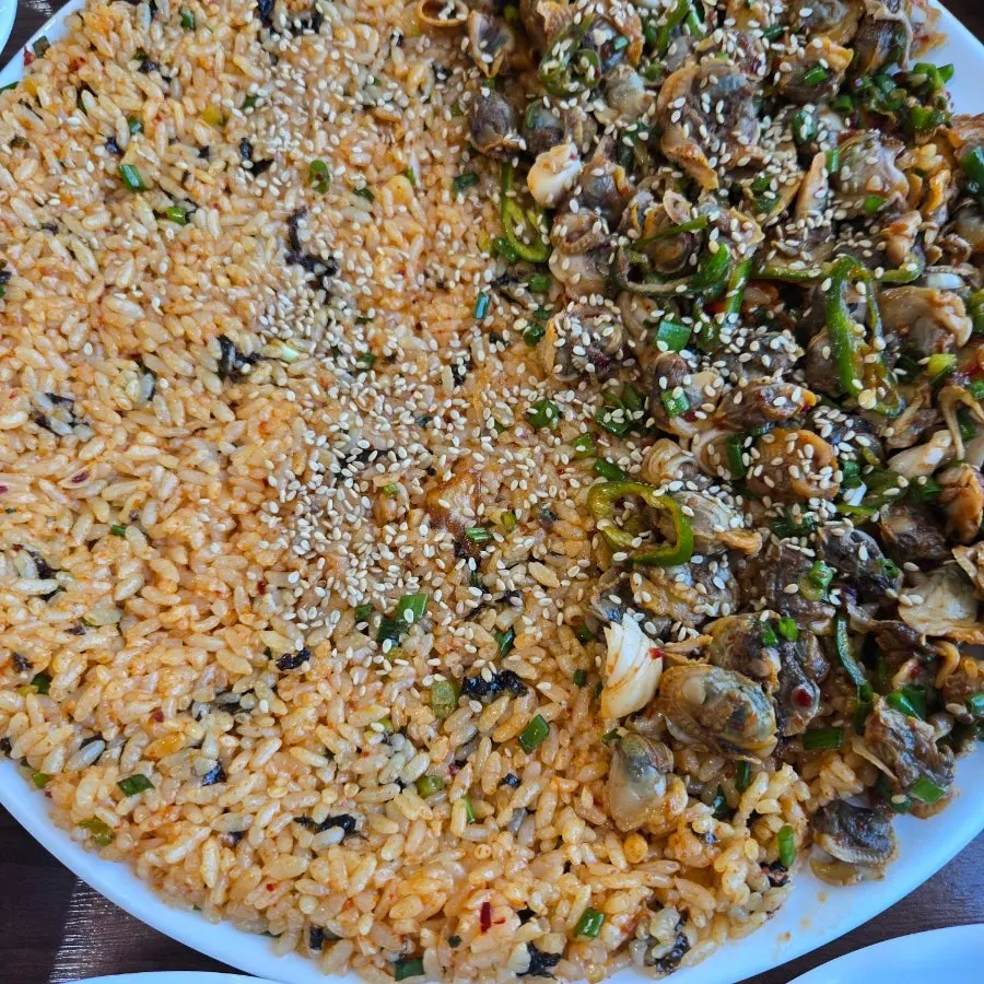 커다란 접시에 담긴 양념 꼬막과 비빔밥