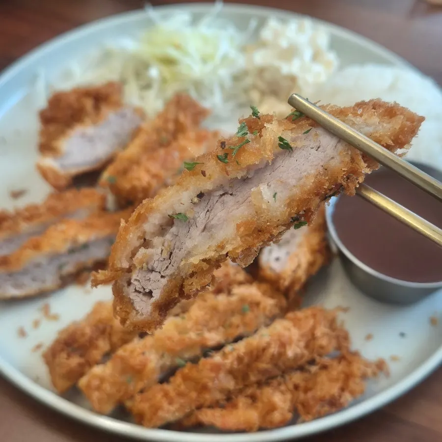 Cross-section of the crispy pork cutlet next to gukbap