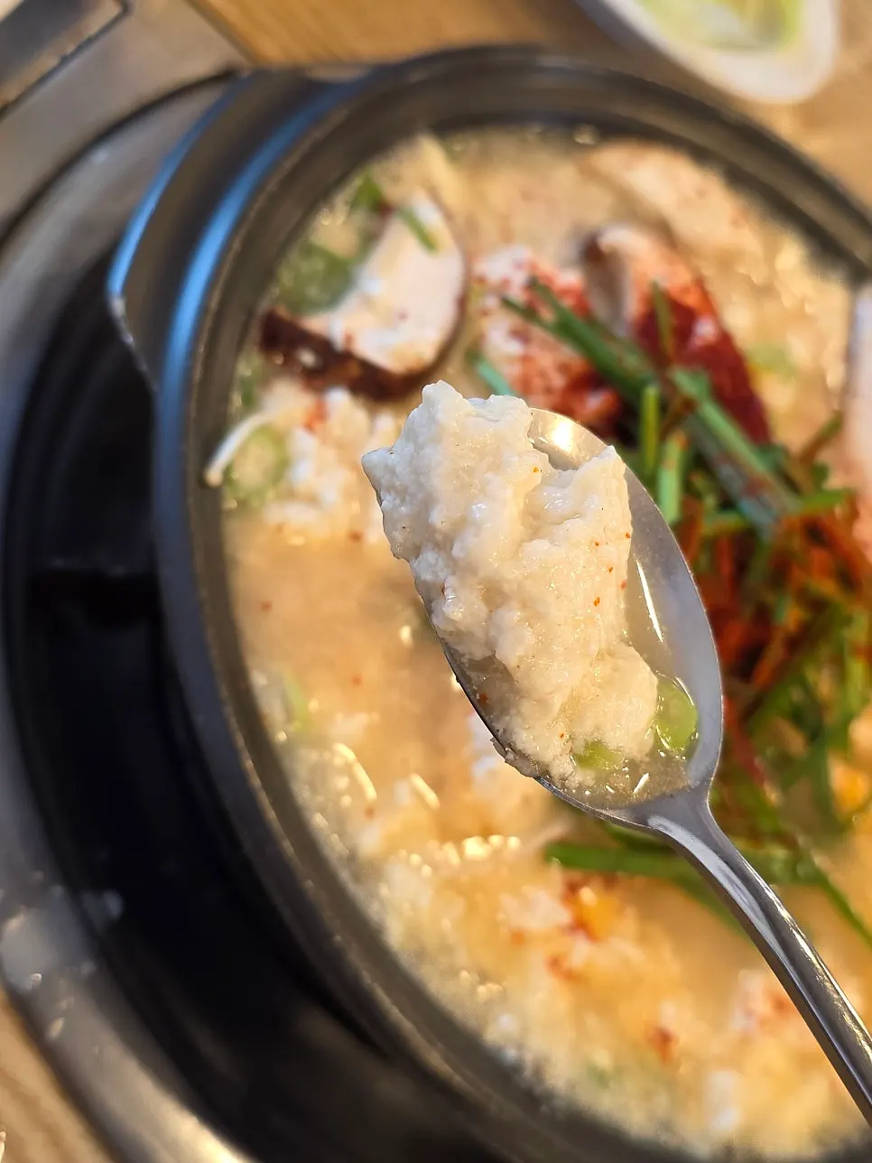 Sundubu jjigae topped with chives and mushrooms