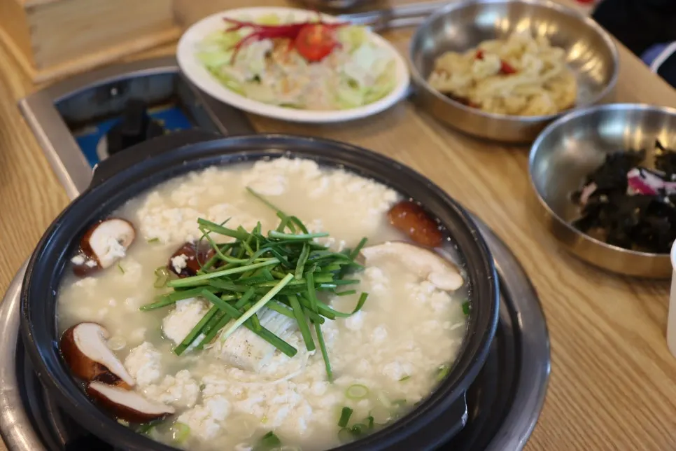 A spoonful of soft, cloudy tofu lifted from the pot