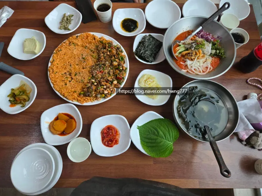 A full table spread with cockle bibimbap, mulhoe, and side dishes