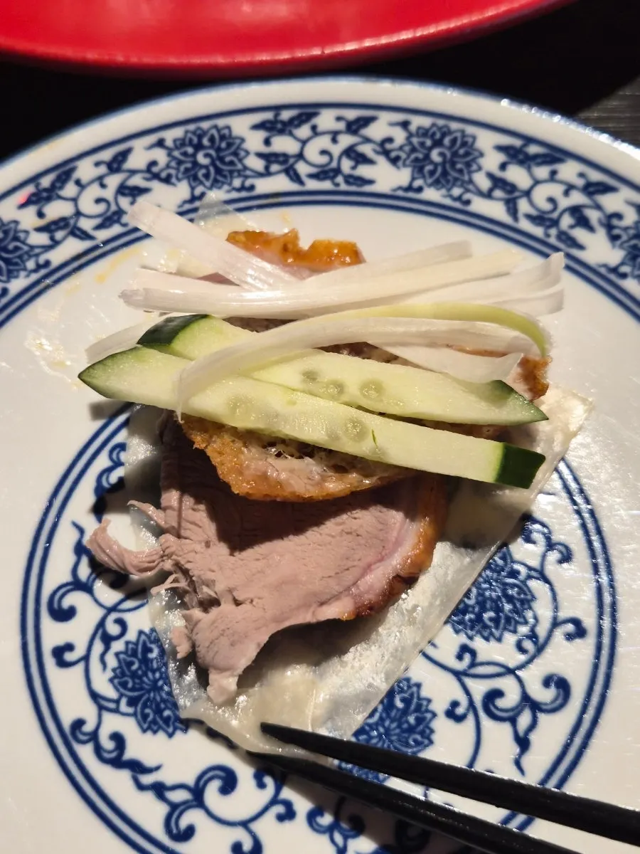 Peking duck wrapped in a pancake with scallion and cucumber