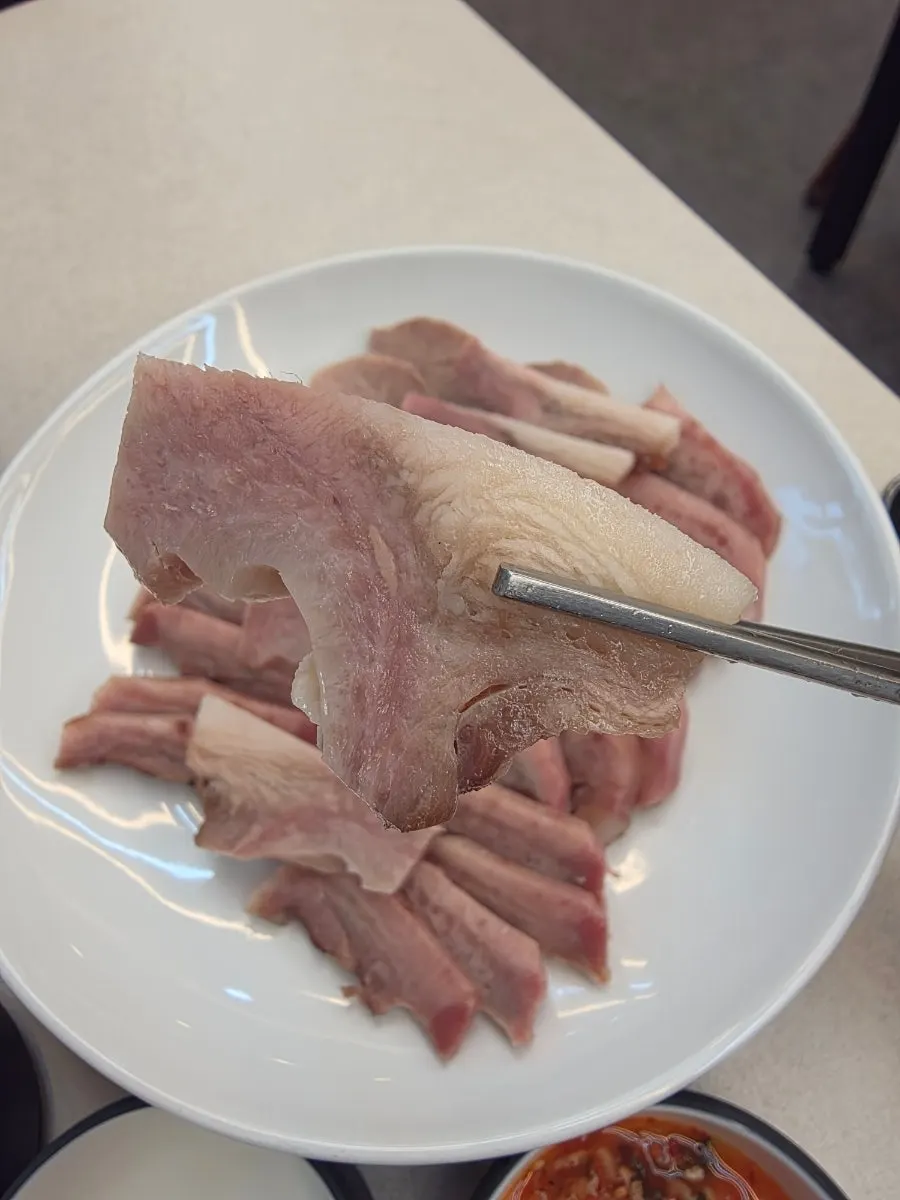 젓가락으로 집은 부드러운 수육 한 점