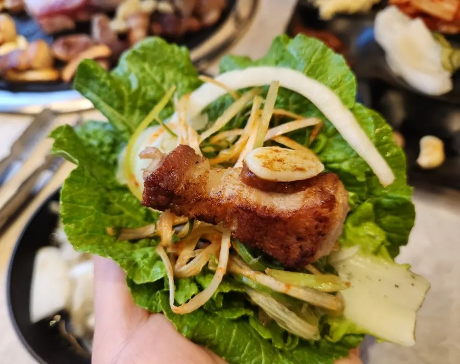Pork belly wrap topped with bracken and scallions
