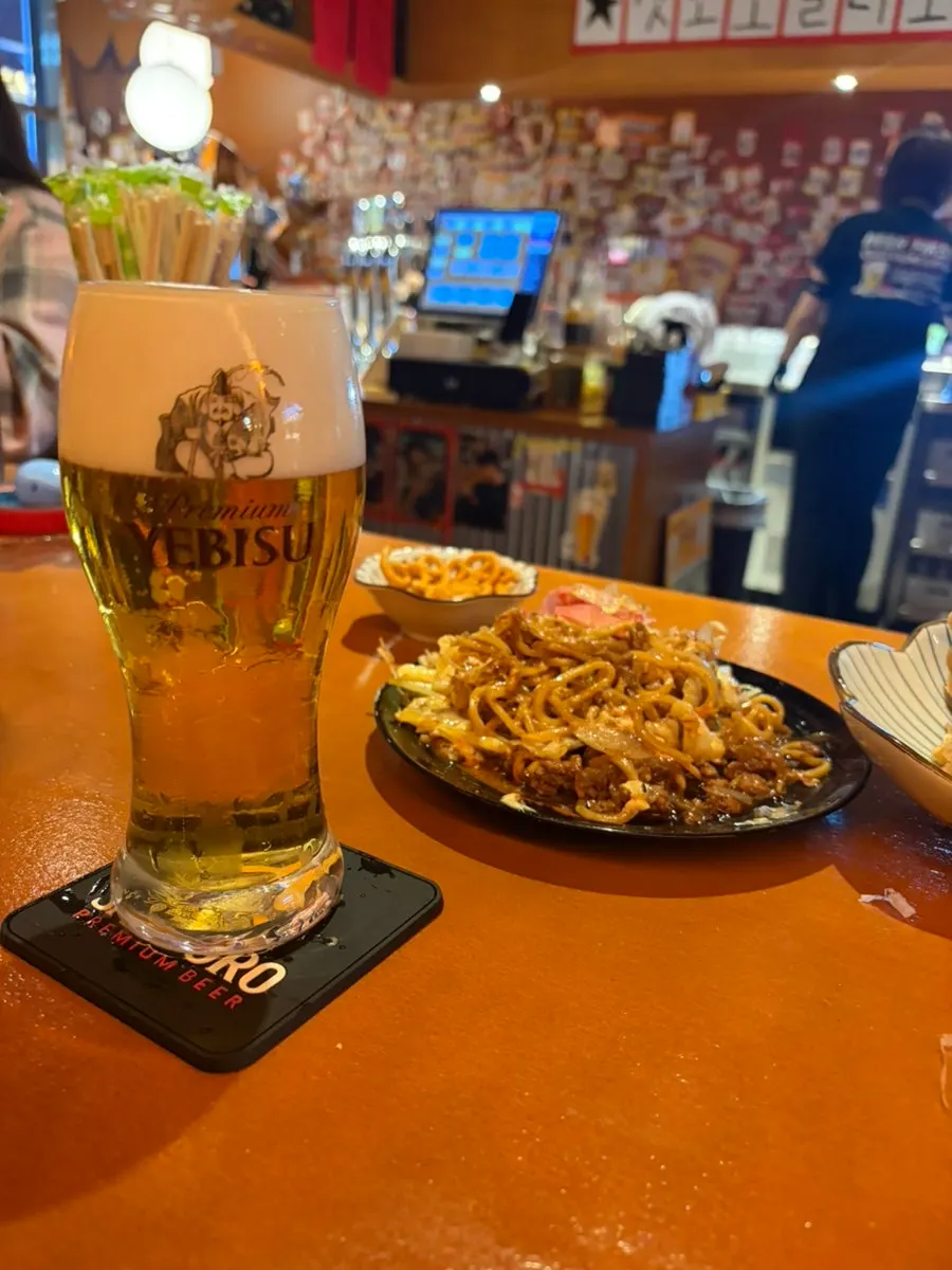 Yakisoba served alongside a glass of draft beer