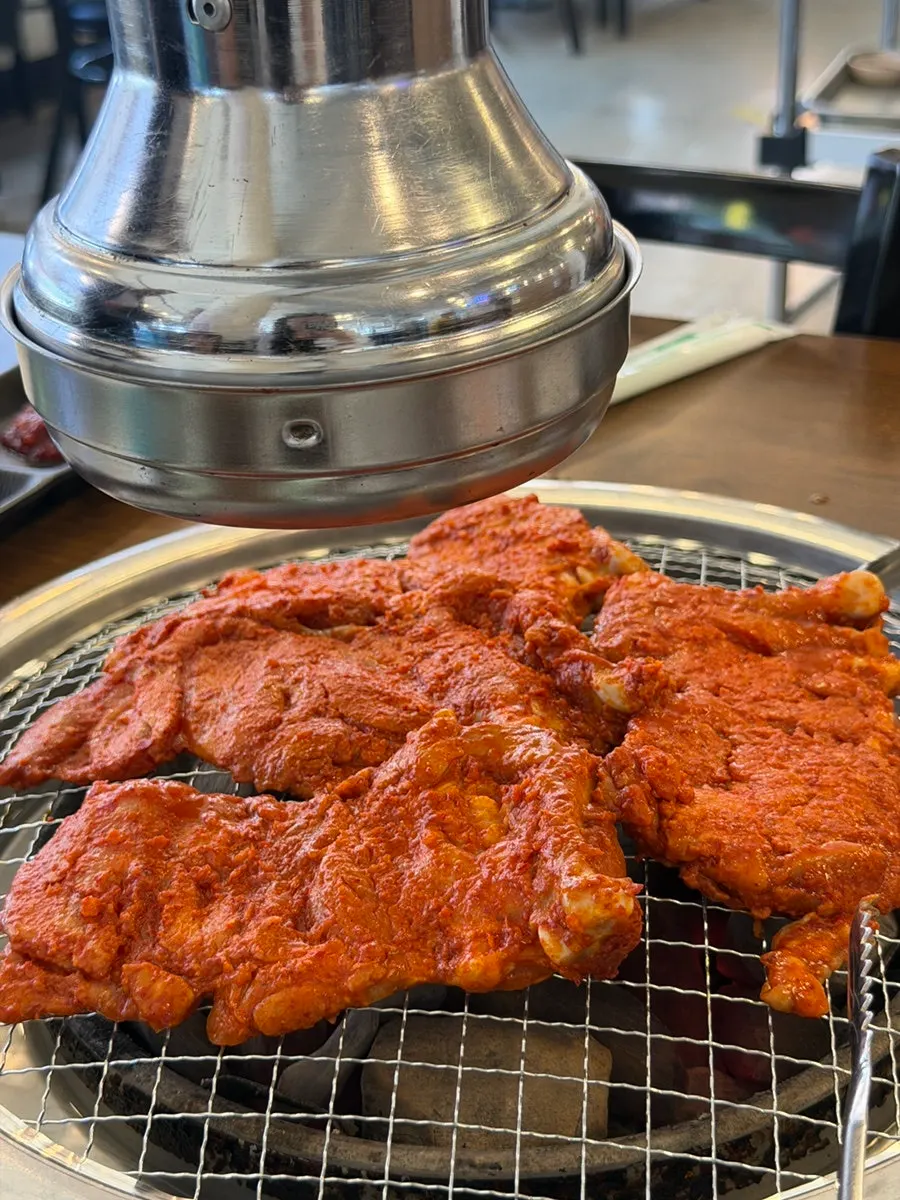 Seasoned dakgalbi grilling over charcoal