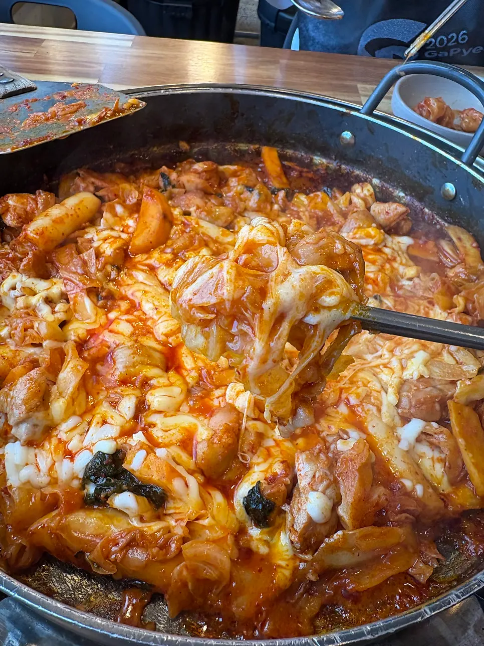 Dakgalbi lifted up with cheese stretching from it