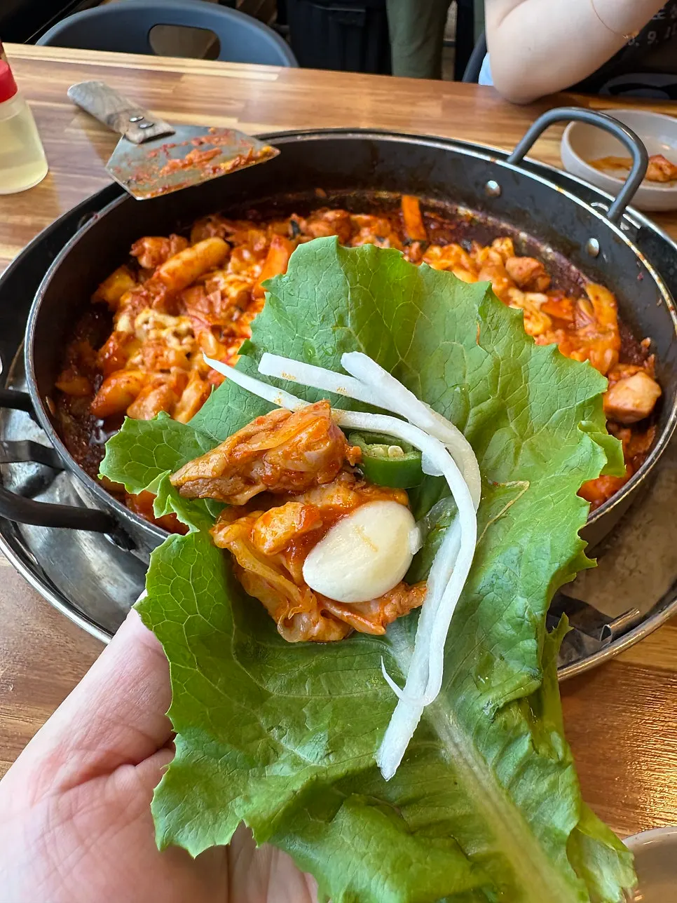 A piece of cheese dakgalbi wrapped in lettuce