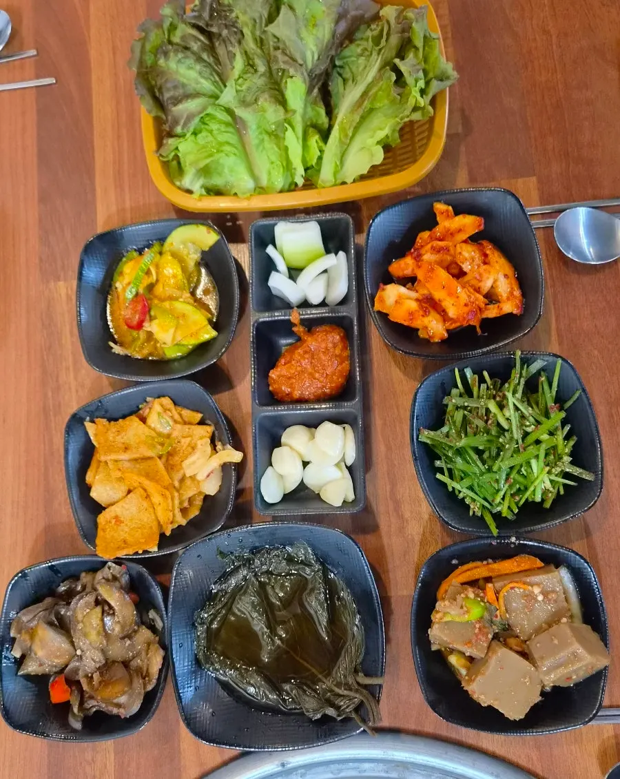 Table of side dishes including fresh deodeok muchim