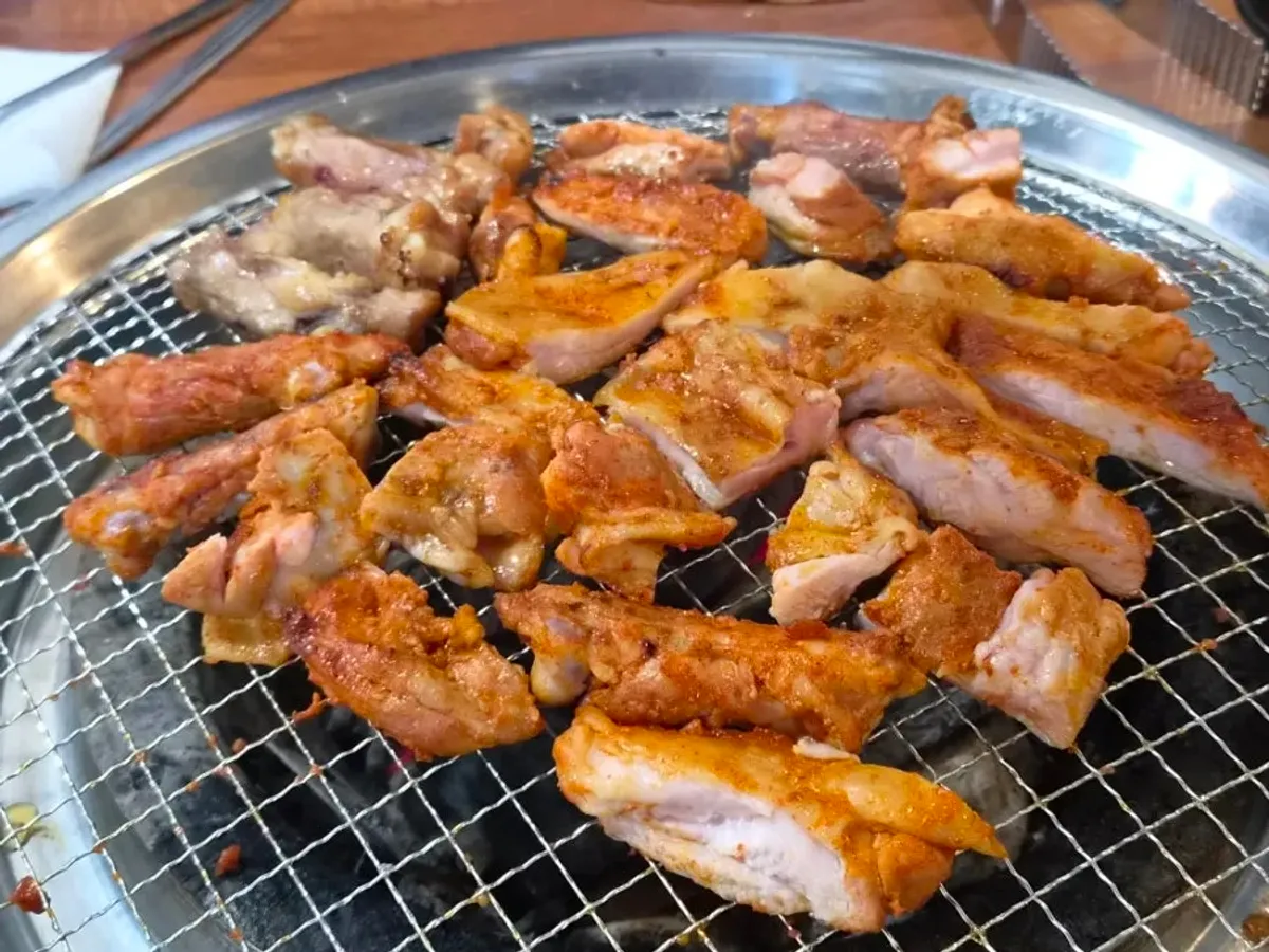 Charcoal-grilled dakgalbi served alongside mul-makguksu