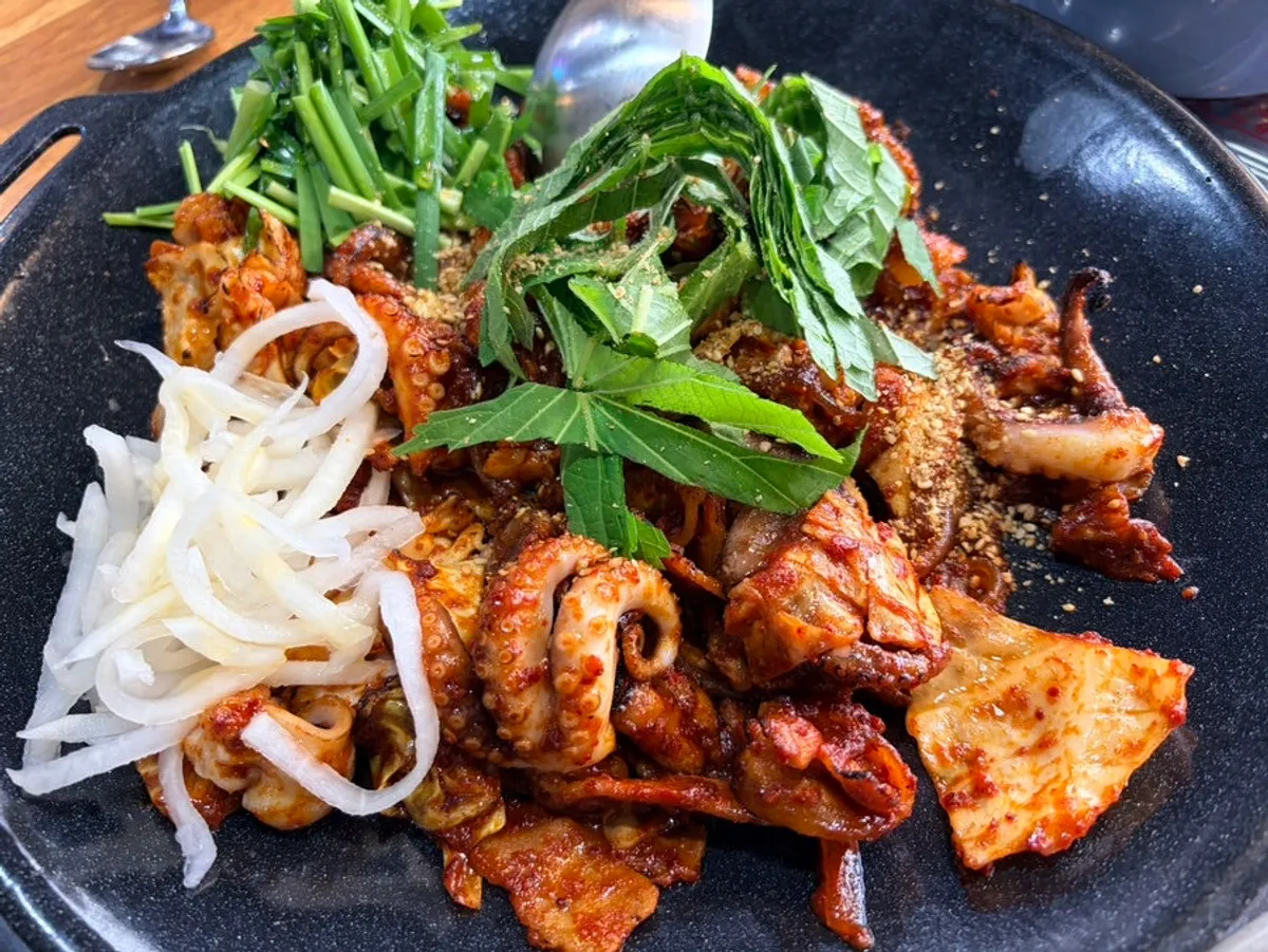 Two servings of grilled octopus and pork on the hot plate