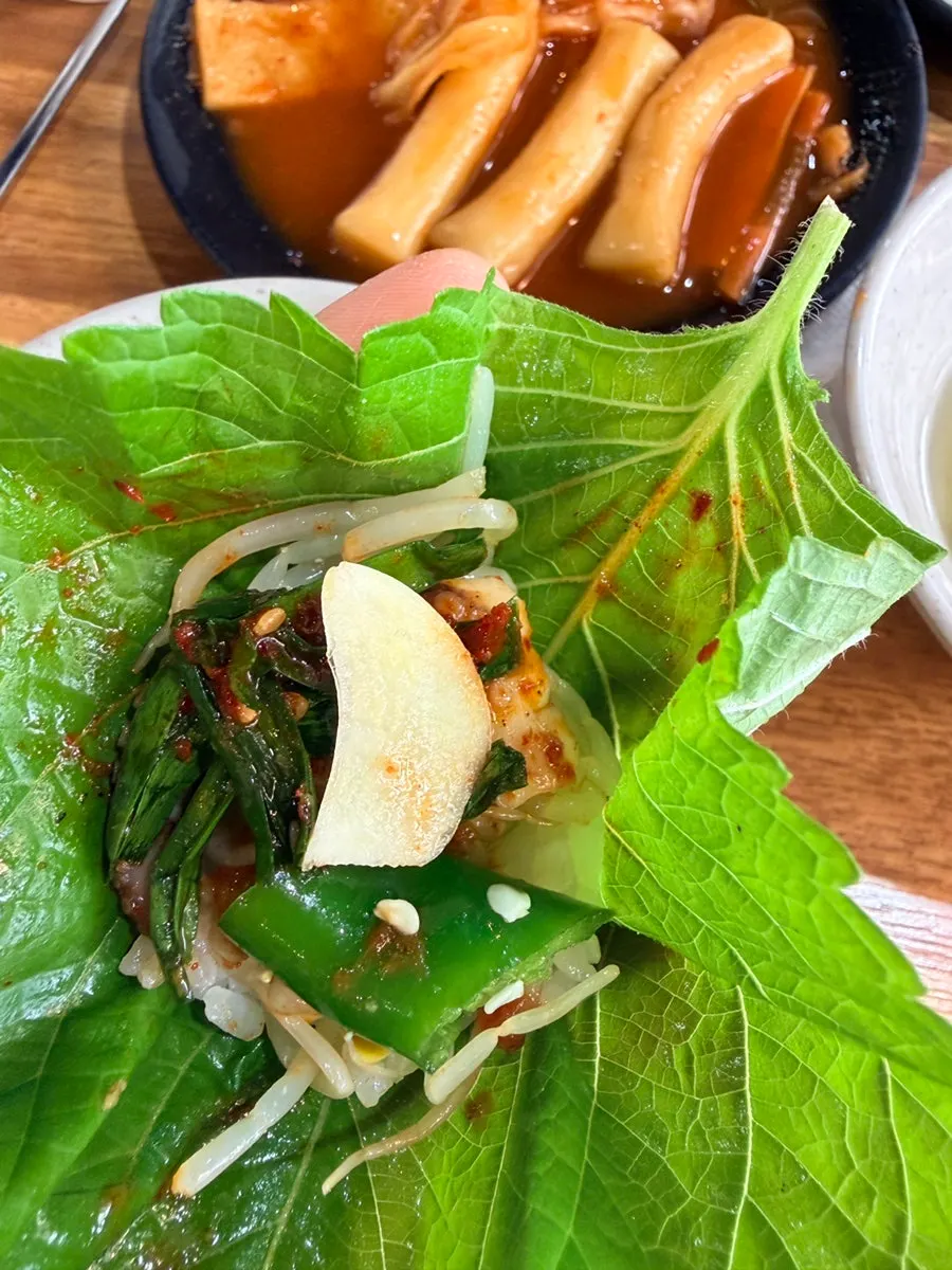 A bite of grilled octopus and pork wrapped in pickled radish