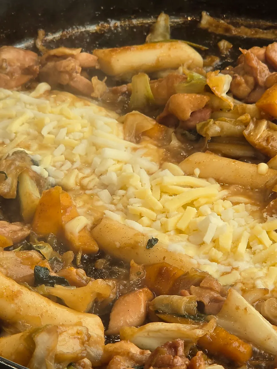 Complimentary cheese melting over the soy sauce dakgalbi