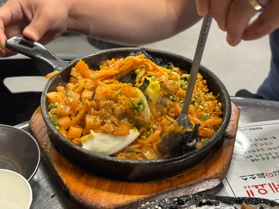 Gopchang dipped in sauce next to grilled green onion kimchi