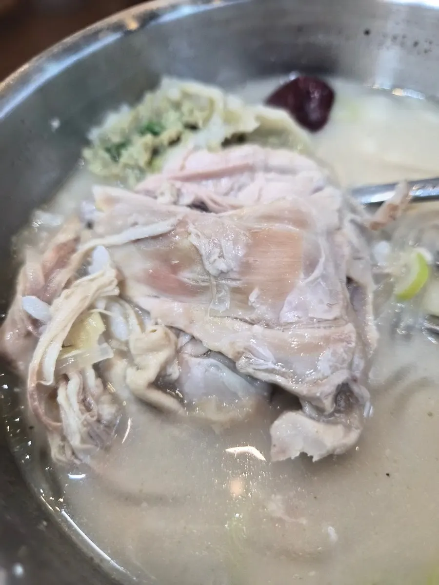 Close-up of the samgyetang kalguksu with a large chicken drumstick on top