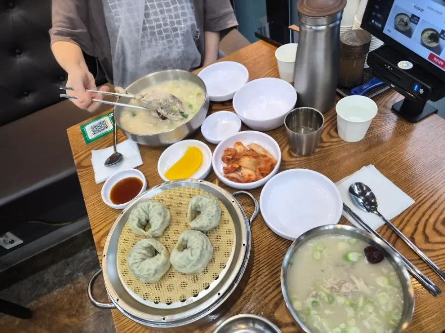 A table set with dak gomtang, samgyetang kalguksu, and king mandu