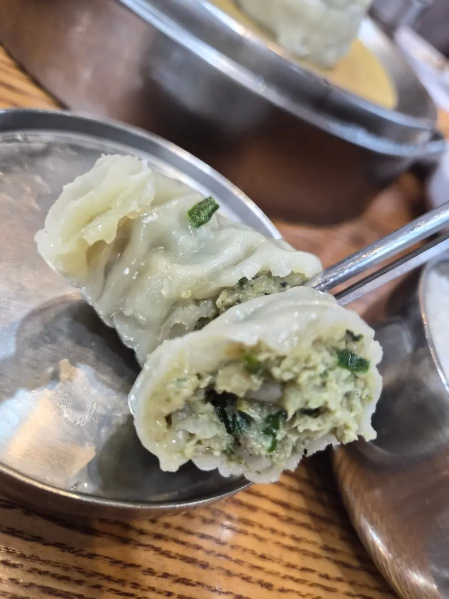 Dunking mandu into the dak gomtang broth
