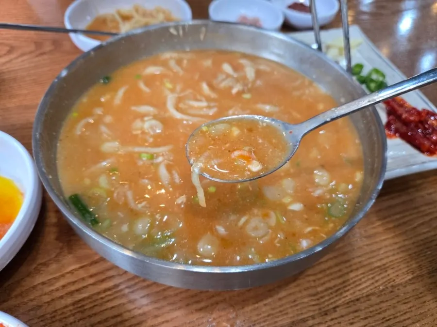 A bite of kalguksu topped with spicy kimchi