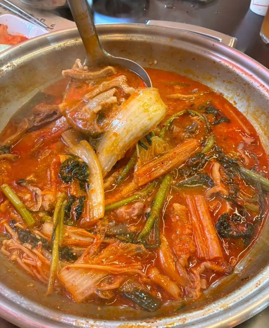 A bite of cabbage kimchi and gopchang hot pot