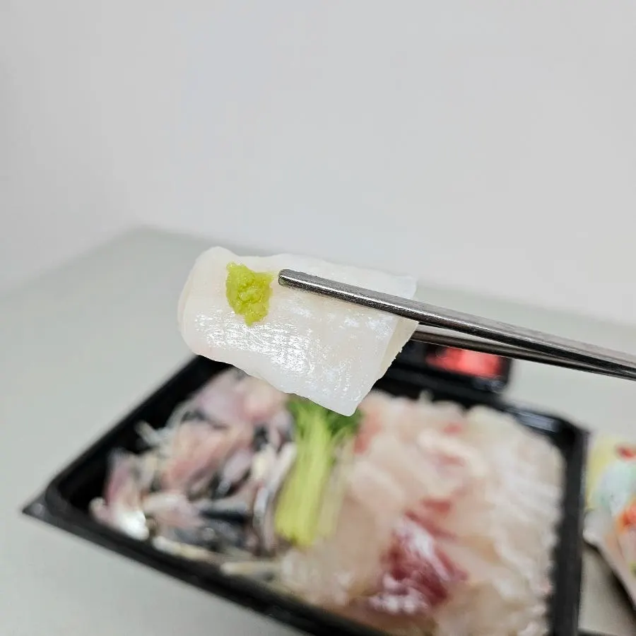 A piece of mixed sashimi picked up with chopsticks