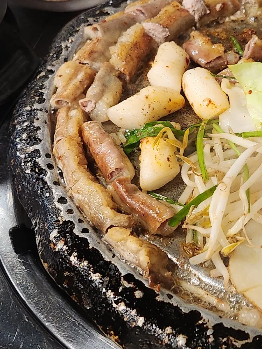 A piece of beef gopchang dipped in garlic sauce