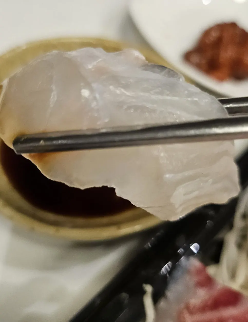 A thick piece of sashimi held with chopsticks
