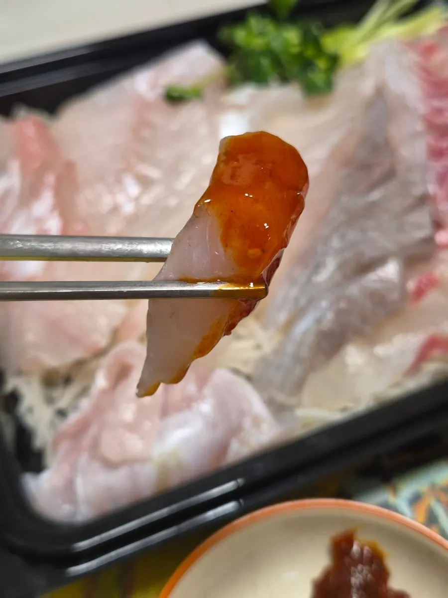 A piece of sashimi dipped in chojang sauce