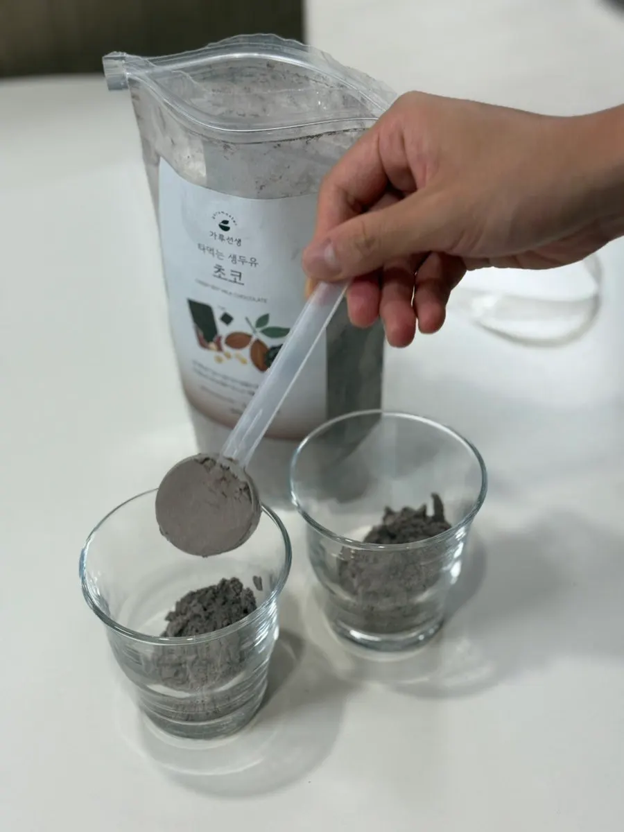 Two scoops of chocolate soy milk powder in a cup
