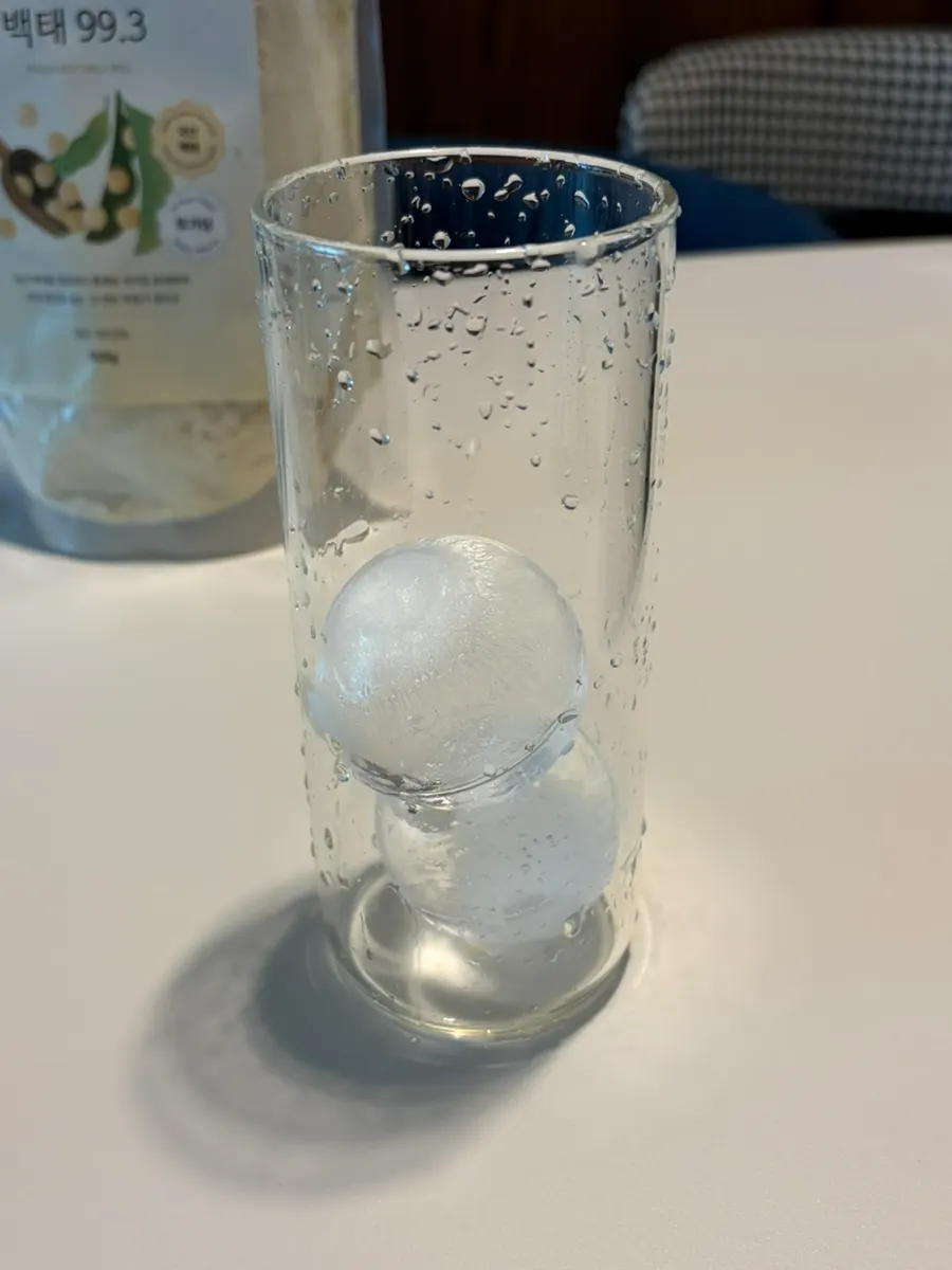 얼음 두 개 넣은 유리컵과 백태 두유 가루