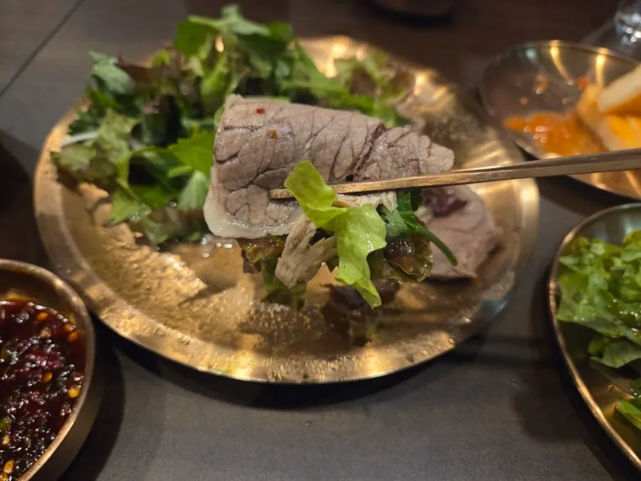Dipping a piece of suyuk into the sauce