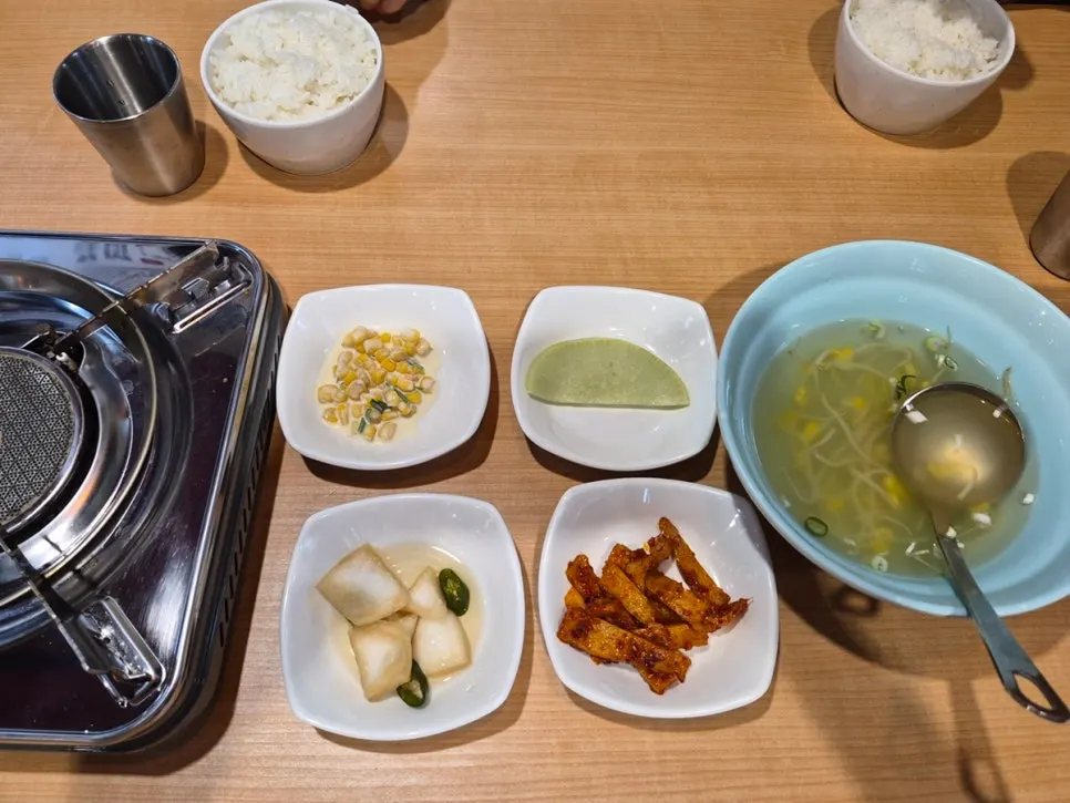 Table of side dishes including radish wrap, fish cake, and corn salad