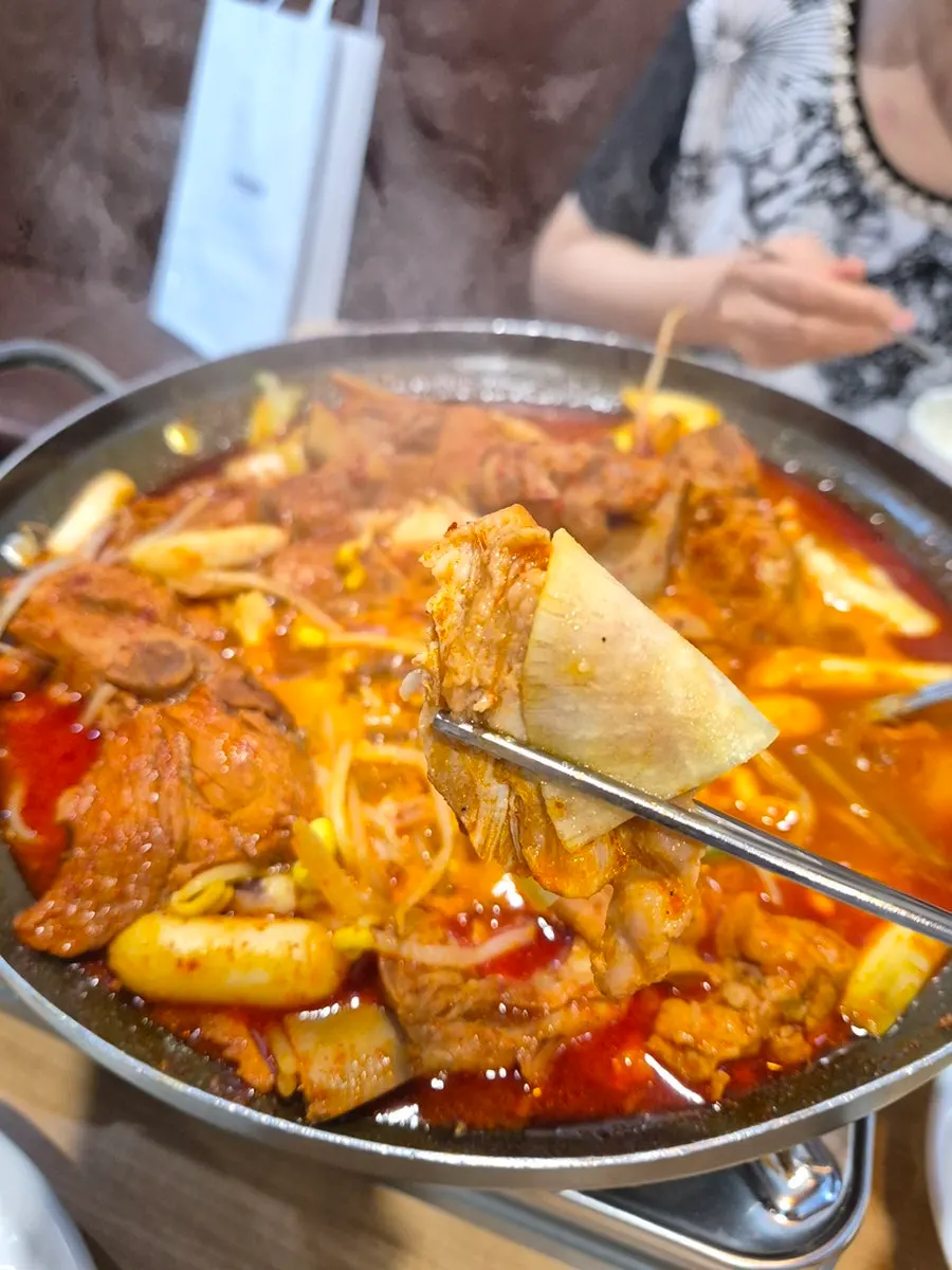 Ladle of sauce-soaked ribs and bean sprouts