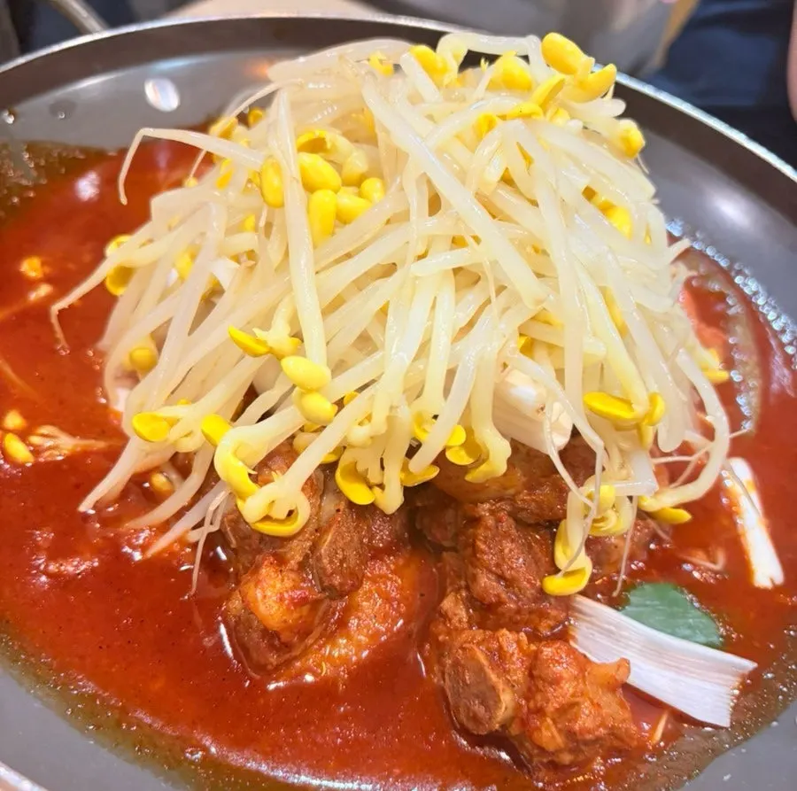 Braised ribs simmering at the table with bean sprouts mixed into the sauce