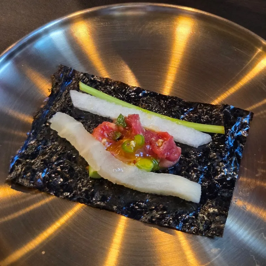 A bite of Yukhwang yukhoe on seaweed